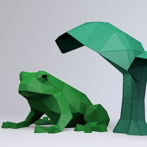 May include: A green origami frog sitting in front of a green origami tree with leaves. The frog and tree are made of paper and have a textured surface.