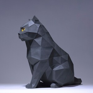 Pode incluir: Uma escultura de gato de origami preto com olhos amarelos. O gato est&aacute; sentado com a cabe&ccedil;a virada para o lado e a cauda enrolada ao redor do corpo.