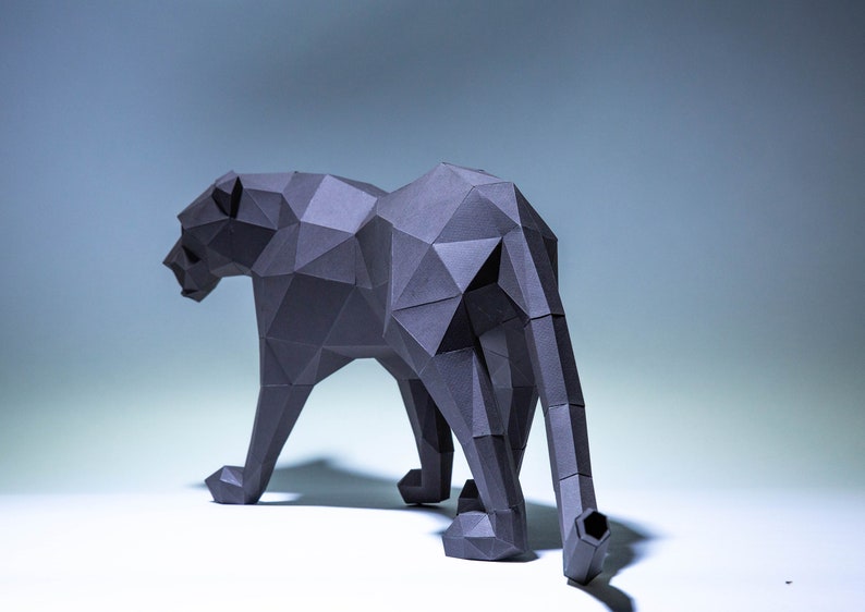 May include: A black papercraft sculpture of a panther, standing on a white surface. The panther is made of many small triangles, giving it a geometric look.