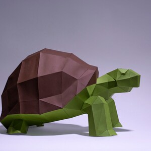 May include: An origami turtle sculpture made from brown and green paper. The turtle's shell is brown and its body and legs are green.