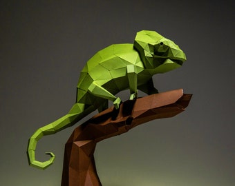 May include: A green origami chameleon perched on a brown origami branch. The chameleon is made of folded paper and has a detailed, realistic design.