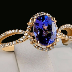 May include: A gold ring with a large oval-shaped blue gemstone surrounded by smaller diamonds. The ring has a delicate, twisted band.