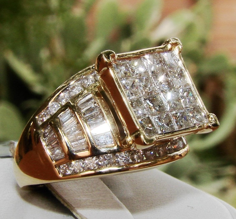 May include: A gold ring featuring a large square-shaped diamond centre stone surrounded by smaller diamonds. The ring is set in a gold band with a row of baguette-shaped diamonds.
