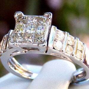 May include: A silver engagement ring with a large square-shaped center diamond and a band of smaller diamonds.