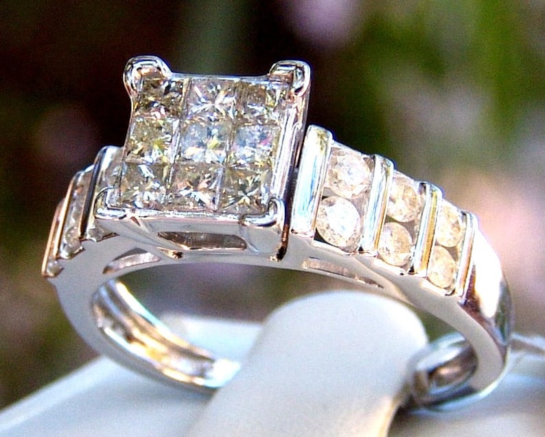 May include: A silver engagement ring with a large square-shaped center diamond and a band of smaller diamonds.