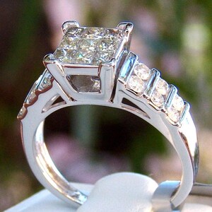 May include: A silver engagement ring with a large square-cut diamond center stone and smaller diamonds set in the band.