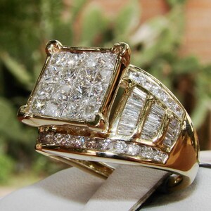 May include: A gold ring featuring a large square-shaped centre stone surrounded by smaller diamonds. The band is also set with diamonds in a baguette cut.
