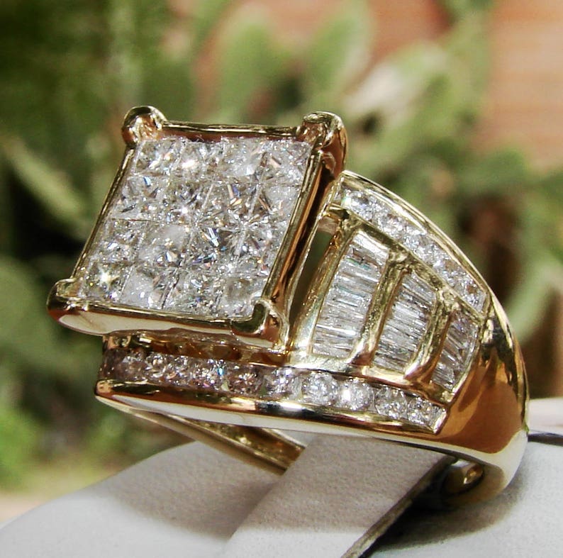 May include: A gold ring featuring a large square-shaped centre stone surrounded by smaller diamonds. The band is also set with diamonds in a baguette cut.