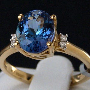 May include: A gold ring with a large blue oval gemstone and two smaller diamond accents.