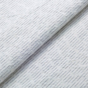 Może przedstawiać: Biała tkanina z subtelnym wzorem niebieskich prążków. Tkanina jest złożona na pół, pokazując fakturę i splot materiału.