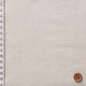 May include: A close-up of a beige fabric with a brown button in the bottom right corner. The fabric has a woven texture.