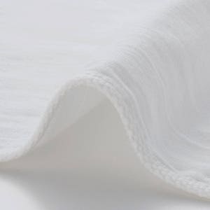 May include: Close-up of a white fabric with a textured surface. The fabric is folded over, showing the edge of the material.