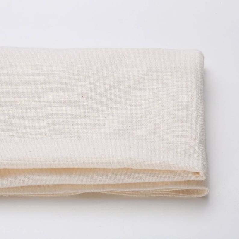 May include: A folded white cotton fabric, possibly a tea towel or dishcloth.