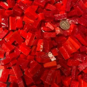 May include: A large pile of red glass mosaic tiles. The tiles are in the shape of small bricks. A US quarter is included for scale.