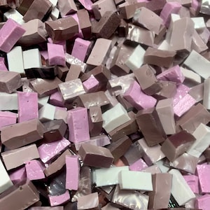 May include: A pile of irregularly shaped mosaic tiles in shades of brown, pink, and white. The tiles vary in size and shape, creating a textured appearance. Ideal for craft projects.