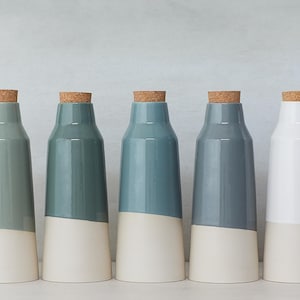 May include: Five ceramic bottles with cork stoppers. The bottles are in shades of blue and white. The bottles are all the same size and shape.