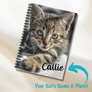 May include: A spiral bound notebook featuring a photograph of a tabby kitten with green eyes. The kitten's name, "Callie", is printed on the cover.
