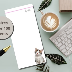May include: A white notepad with a pink line and the name "Cynthia" written in black cursive. The notepad has a picture of a cute kitten with brown, white, and gray fur. The notepad is available in 3 sizes with 50 or 100 sheets.