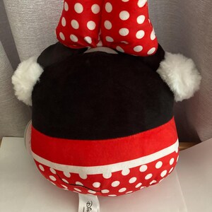 Op de afbeelding: Een Minnie Mouse knuffel met een rode en witte polka dot strik, zwarte kop en rode en witte polka dot rok. De knuffel heeft witte, pluizige oren en een Disney-label.