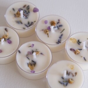 Puede incluir: Seis velas de t&eacute; blancas en recipientes de vidrio transparente. Cada vela tiene una mecha y est&aacute; incrustada con lavanda seca, peque&ntilde;os cristales morados y flores secas.