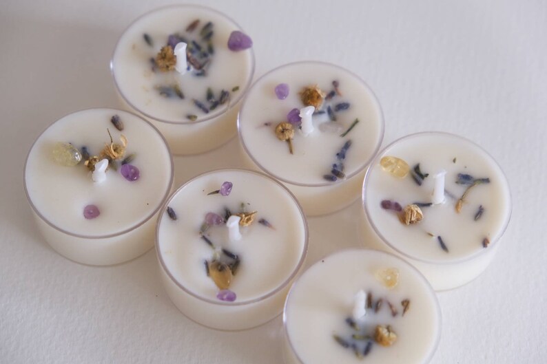 Puede incluir: Seis velas de t&eacute; blancas en recipientes de vidrio transparente. Cada vela tiene una mecha y est&aacute; incrustada con lavanda seca, peque&ntilde;os cristales morados y flores secas.