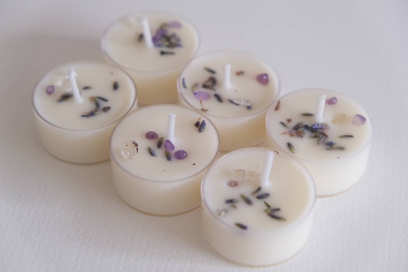 Puede incluir: Seis velas de t&eacute; blancas con lavanda y peque&ntilde;os cristales morados y transparentes incrustados en la cera.