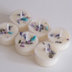 Puede incluir: Seis velas de t&eacute; con flores secas y piedras turquesa incrustadas. Las velas son blancas y tienen un recipiente de pl&aacute;stico transparente.