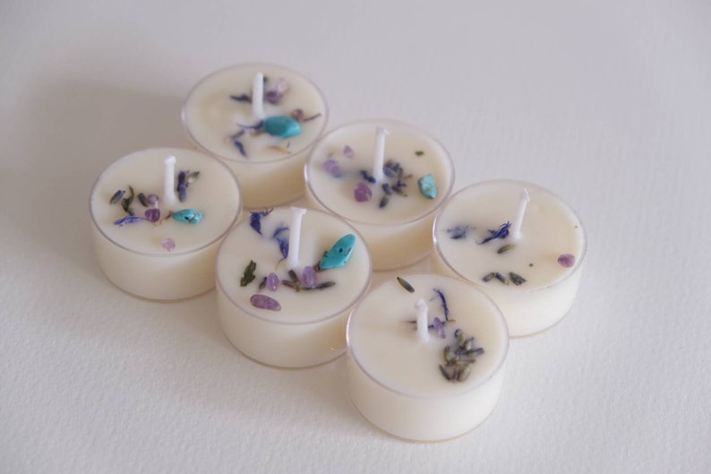Puede incluir: Seis velas de t&eacute; con flores secas y piedras turquesa incrustadas. Las velas son blancas y tienen un recipiente de pl&aacute;stico transparente.