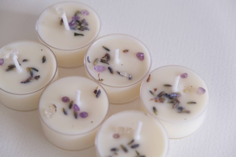Puede incluir: Seis velas de t&eacute; blancas con lavanda y peque&ntilde;os cristales morados y transparentes incrustados en la cera.