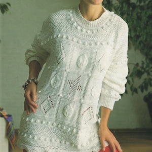 May include: White knitted sweater with a textured design featuring a variety of geometric shapes and bobbles.