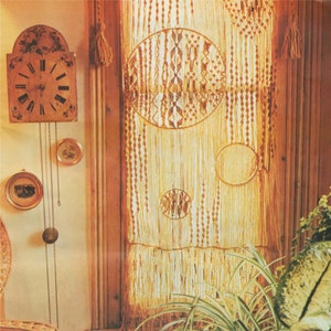 Könnte beinhalten: Ein Makramee-Vorhang mit Fransen unten hängt an einem Fenster. Der Vorhang hat ein gewebtes Muster aus Kreisen. Vor dem Fenster steht eine Topfpflanze.