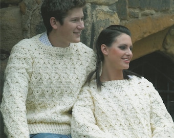 May include: Two people wearing white crocheted sweaters with a cable knit pattern. The sweaters are worn over blue jeans.