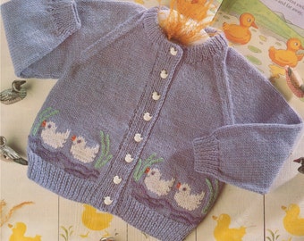 May include: A light purple knitted baby cardigan with a button closure and embroidered ducks on the front. The cardigan is surrounded by toy ducks.
