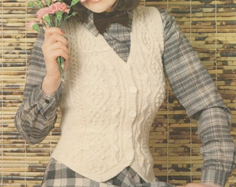 May include: A white knitted vest with a cable knit pattern and button closure. The vest is worn over a plaid shirt and a black bow tie.