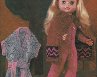 May include: A knitted doll outfit with a brown cape, pink pants, and a matching pink and gray dress. The doll is wearing the outfit and has blonde hair and blue eyes.