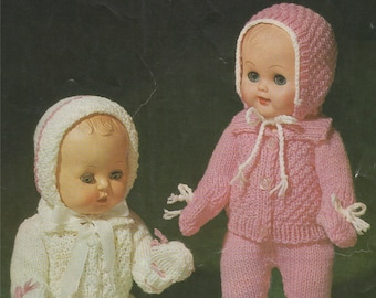 May include: Two knitted doll outfits, one in white with pink trim and one in pink with white trim. Both outfits feature a hat, jacket, and pants.