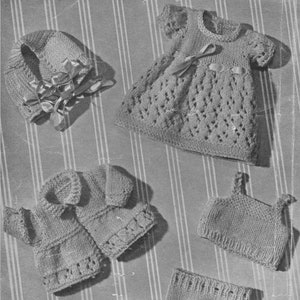 Pode incluir: Um conjunto de roupas de bebé de malha em cor castanho claro, incluindo um vestido, uma jaqueta, um chapéu, uma blusa e uma calça.