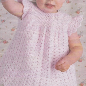 May include: A little girl wearing a pink crocheted dress with a scalloped hem.