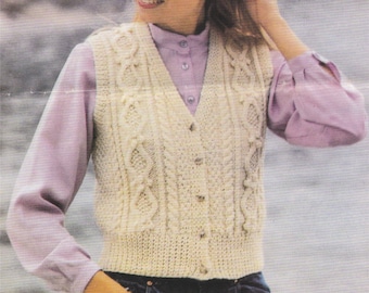May include: A white knitted vest with a cable knit pattern and button closure. The vest is worn over a light purple shirt and blue jeans.