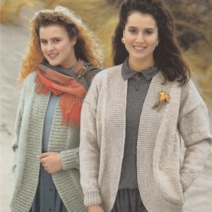 May include: Two women wearing knitted cardigans. The woman on the left is wearing a light green cardigan with a red and white scarf. The woman on the right is wearing a beige cardigan with a gray shirt underneath.