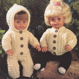 Puede incluir: Dos conjuntos de punto para muñecas, uno en blanco con capucha y el otro en blanco con estilo de cárdigan. Ambas muñecas llevan pantalones negros y botines blancos.