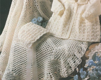 May include: A white crocheted baby blanket with a matching crocheted bonnet and a white knitted cardigan. The blanket has a scalloped edge and a satin ribbon tied around it.