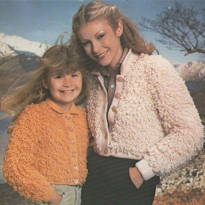 Könnte beinhalten: Zwei Personen tragen flauschige Strickjacken. Die Frau trägt eine weiße Strickjacke und das Mädchen trägt eine orangefarbene Strickjacke. Beide Strickjacken haben Knopfleisten.