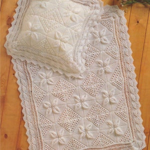 Puede incluir: Un conjunto de manta y almohada para bebé de ganchillo blanco con un delicado diseño floral. La manta y la almohada están hechas con un punto de encaje y tienen un borde festoneado.
