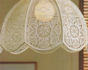 Puede incluir: Una pantalla de lámpara de crochet blanco con un borde festoneado y un delicado patrón floral. La pantalla está colgada de una lámpara de techo.