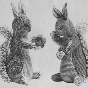 May include: Two grey knitted squirrel toys with fluffy tails. The squirrels are holding small knitted balls in their paws.