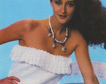 May include: A white crocheted off-the-shoulder top with a ruffled neckline. The top is worn by a woman with long dark hair and a necklace with blue and white beads.