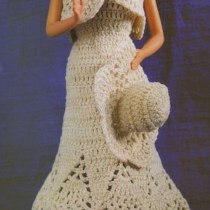 May include: A crocheted dress and matching hat set in a cream color. The dress has a sleeveless bodice and a flowing skirt with a scalloped hem. The hat is a wide-brimmed sun hat.