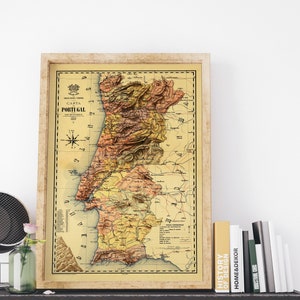 May include: A vintage map of Portugal in a brown frame. The map is in shades of yellow, orange, and brown, with a compass rose in the upper left corner. The title "Carta Portugal" is printed in the upper center of the map.