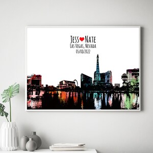 May include: A black and white silhouette of the Las Vegas skyline with a red heart and the text "Jess &hearts; Nate Las Vegas, Nevada 05/08/2022". The skyline is reflected in a body of water with colorful reflections.